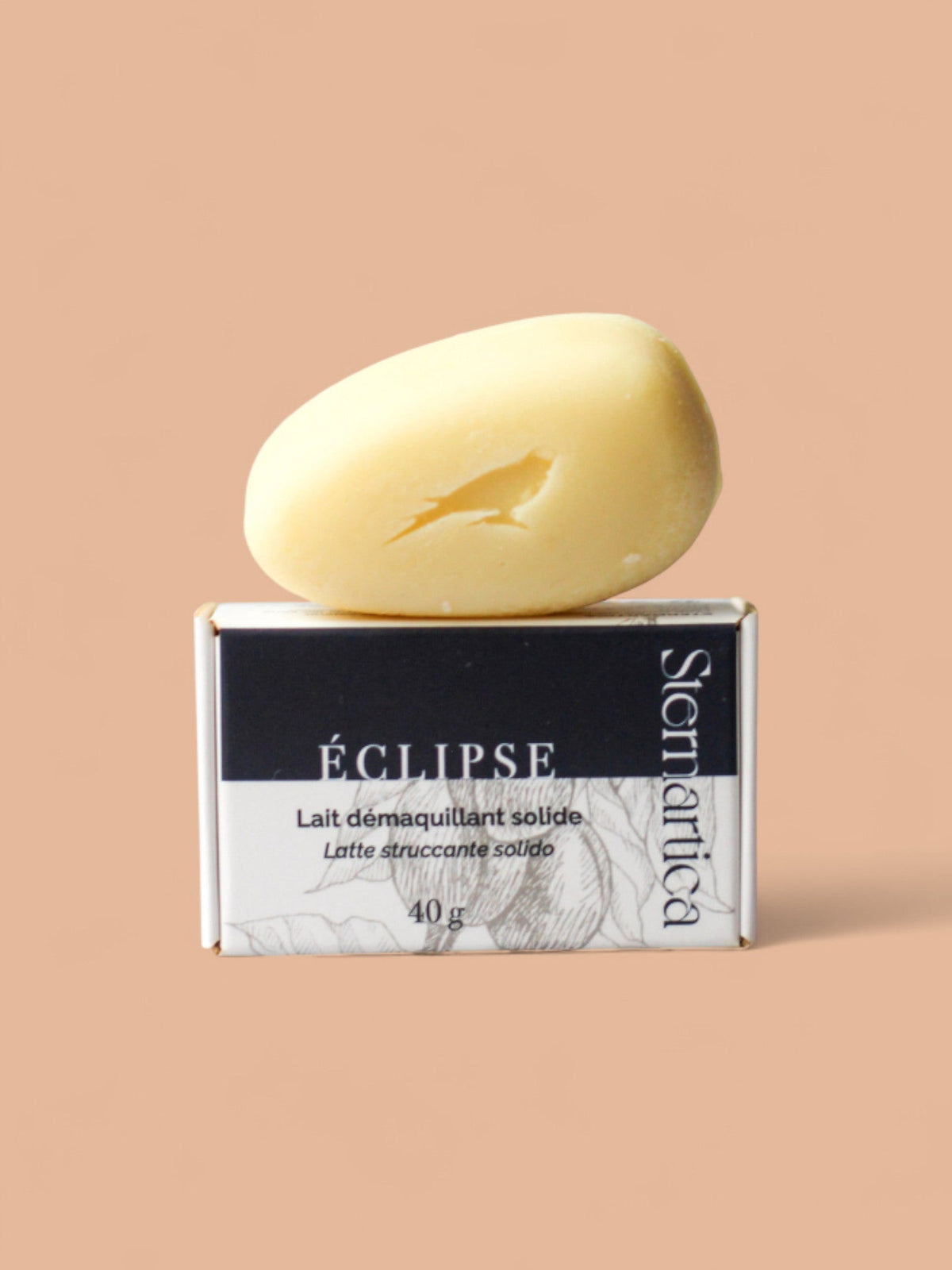 Lait démaquillant solide ÉCLIPSE posé sur son étui noir, format galet 40 g