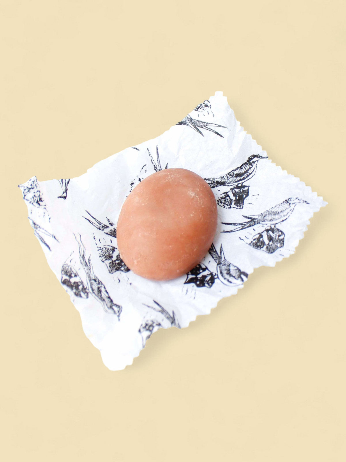 Savon bio format galet posé sur son papier d'emballage imprimé